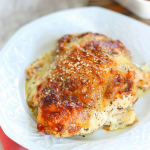 A close-up of golden-brown baked chicken topped with melted cheese in a glass casserole dish.