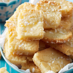 A plate of crispy, coconut-topped shortbread cookies with delicate lacy edges, ready to be enjoyed.