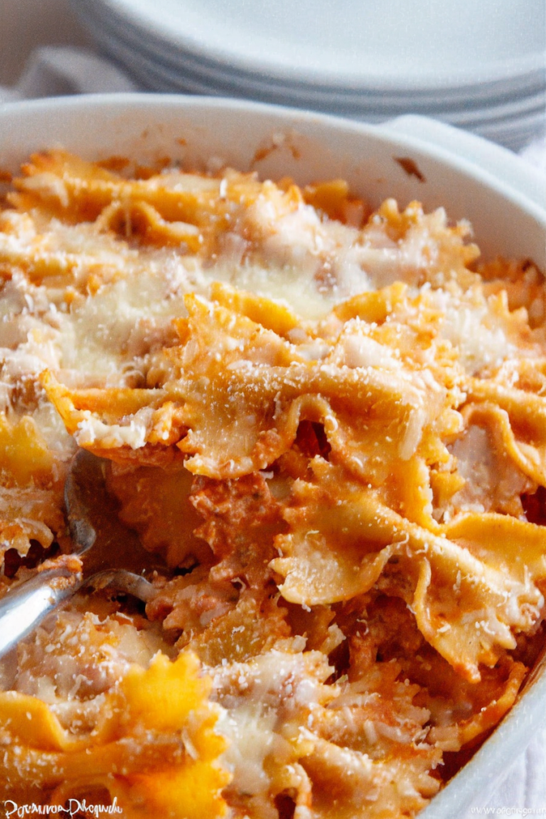 A close-up of cheesy, golden-baked bow tie pasta lasagna topped with melted mozzarella.