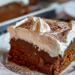 Plated gingerbread cake with soft, spiced layers and a generous dollop of whipped cream.