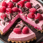 Chocolate Raspberry Mousse Cake decorated with whole raspberries and dark chocolate shavings on a ceramic plate, highlighting the vivid pink mousse and dense chocolate base.