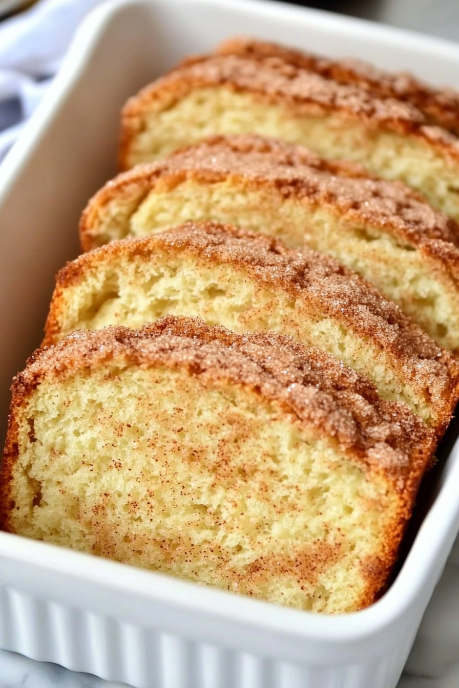 Cinnamon Swirl Cake sliced in a white baking dish, showcasing its moist texture and rich cinnamon sugar layers.