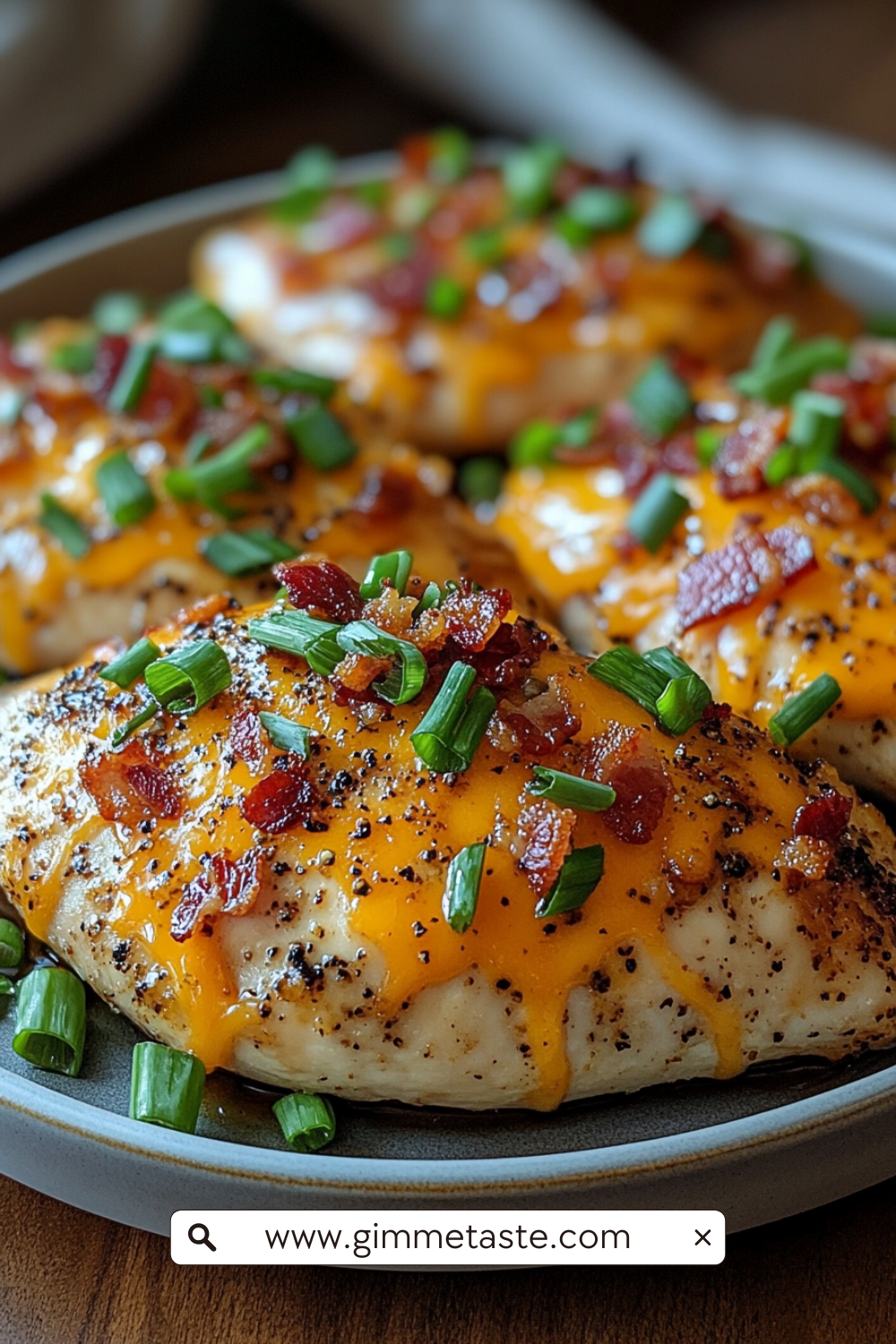 Keto Crack Chicken on a plate, featuring juicy chicken breasts topped with melted cheddar cheese, crispy bacon bits, and chopped green onions, served on a rustic plate.