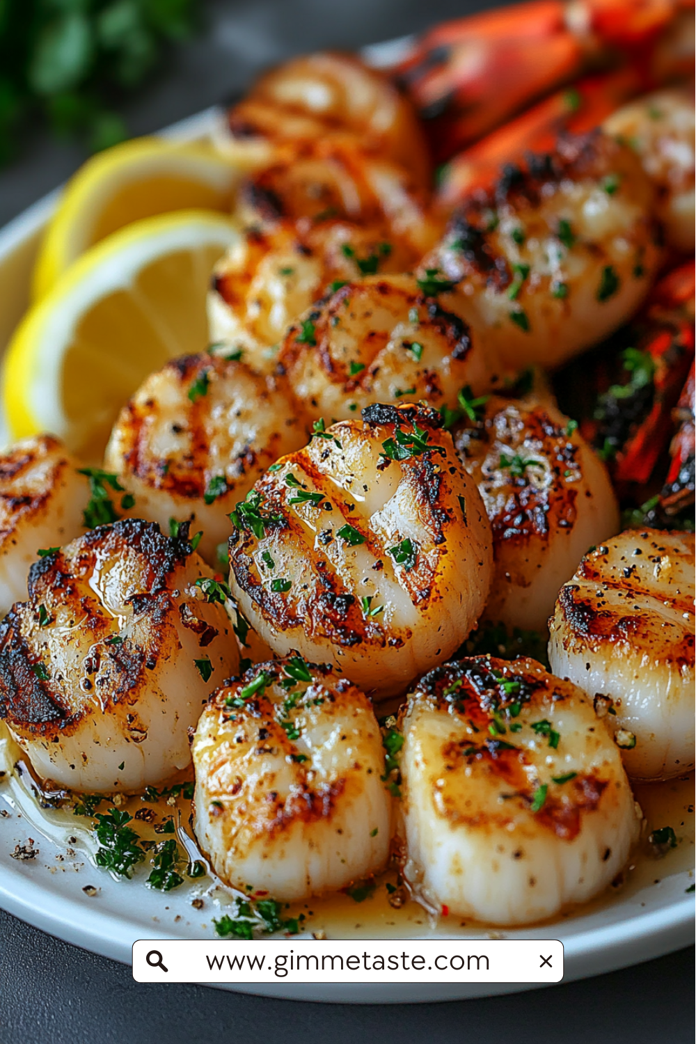 Close-up of garlic butter lobster and scallops garnished with parsley, served with golden roasted squash and lemon slices on a white plate.