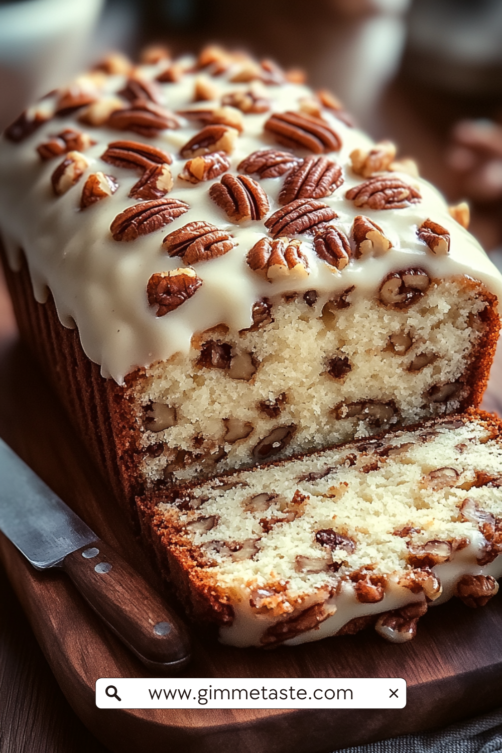 Butter Pecan Cake Loaf with cream cheese icing and toasted pecans on a wooden board, sliced to show its moist, nutty interior.