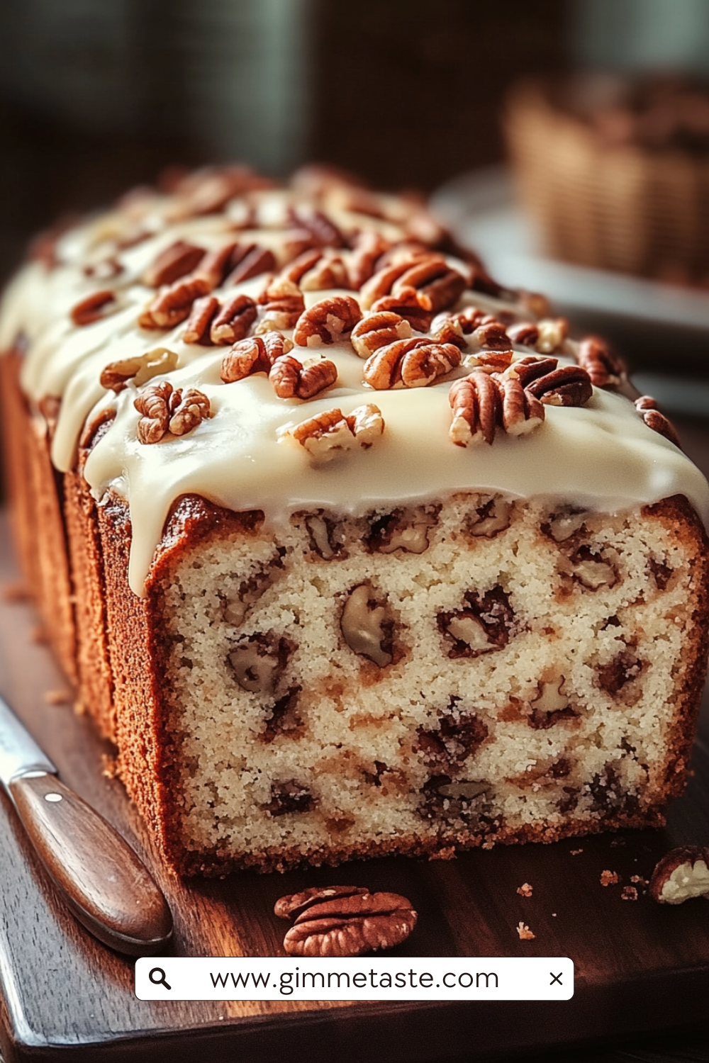 Butter Pecan Cake Loaf with cream cheese icing and toasted pecans on a wooden board, sliced to show its moist, nutty interior.