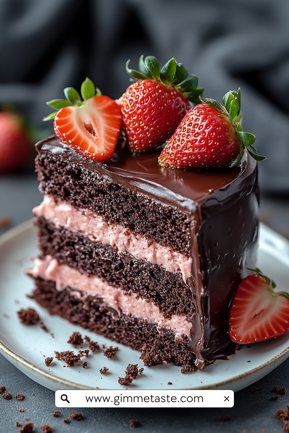 A decadent chocolate layer cake filled and topped with pink strawberry frosting, adorned with whole and halved fresh strawberries and edible flowers.