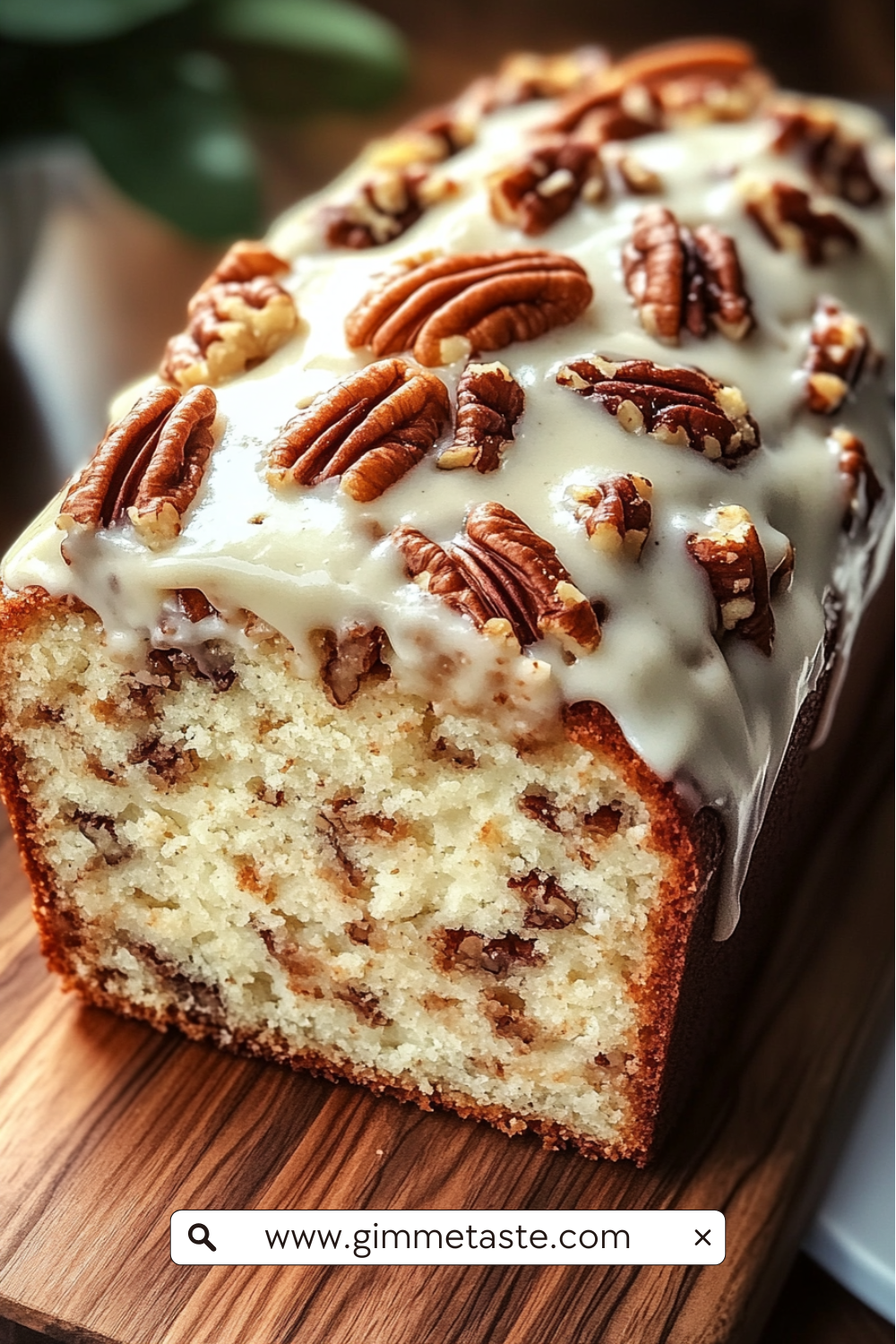 Butter Pecan Cake Loaf with cream cheese icing and toasted pecans on a wooden board, sliced to show its moist, nutty interior.