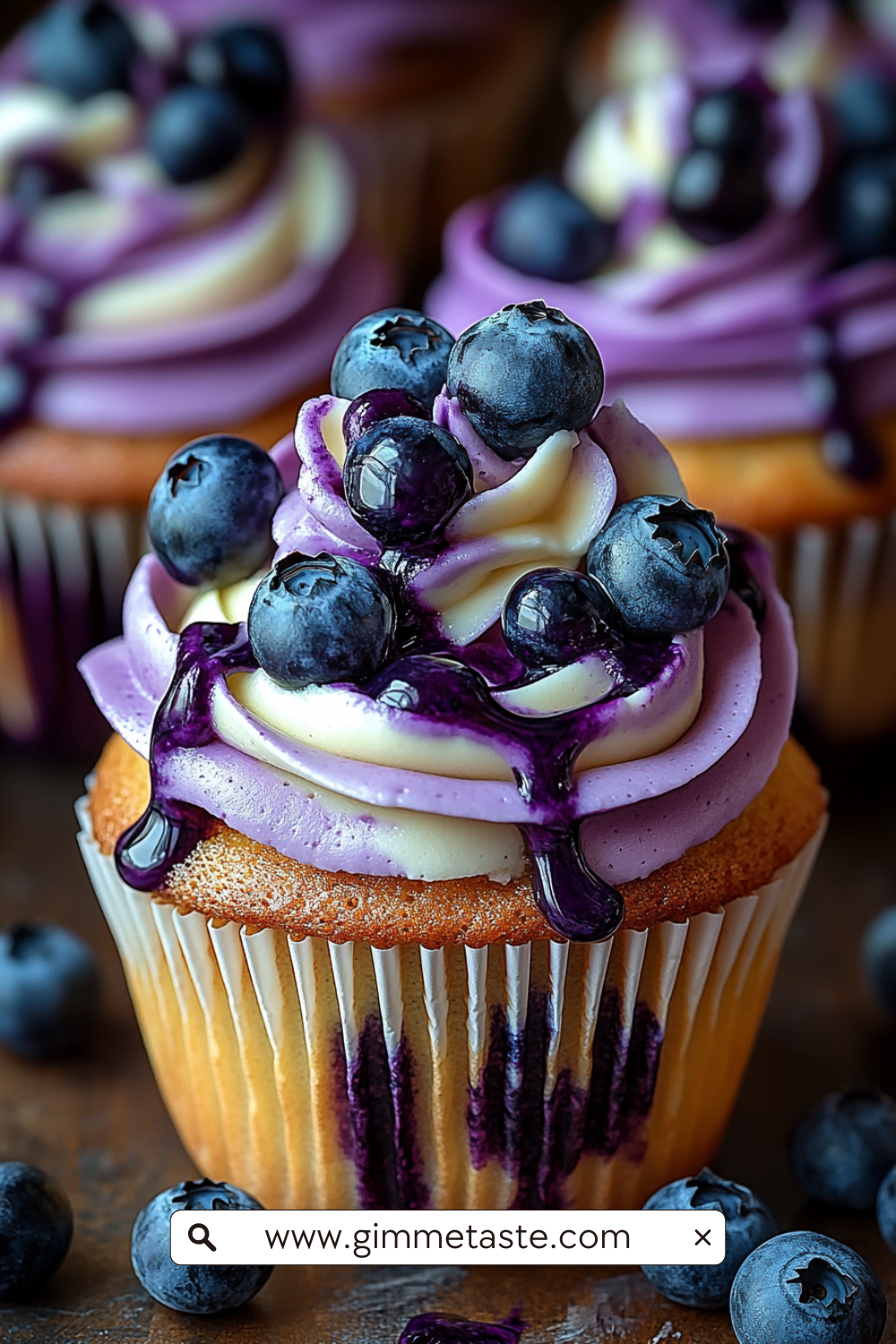 Close-up of White Chocolate Blueberry Cheesecake Cupcakes with swirled cream cheese frosting, blueberry jam drizzle, and fresh blueberries on top.