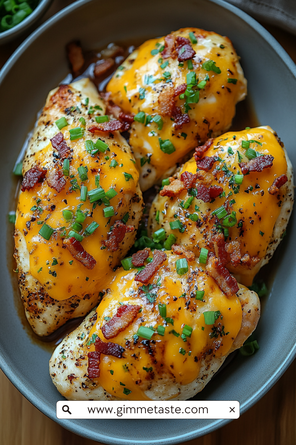 Keto Crack Chicken on a plate, featuring juicy chicken breasts topped with melted cheddar cheese, crispy bacon bits, and chopped green onions, served on a rustic plate.