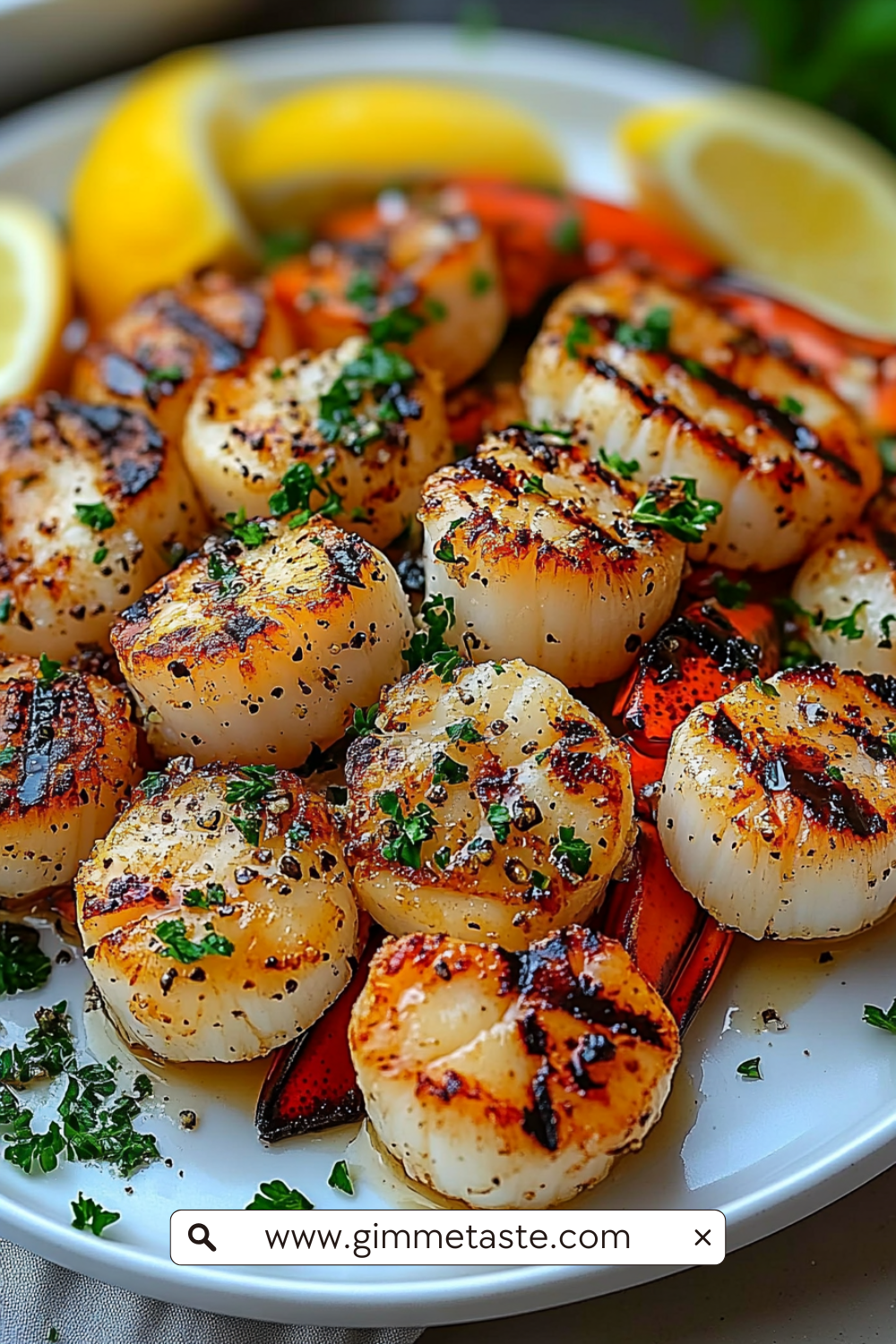 Close-up of garlic butter lobster and scallops garnished with parsley, served with golden roasted squash and lemon slices on a white plate.