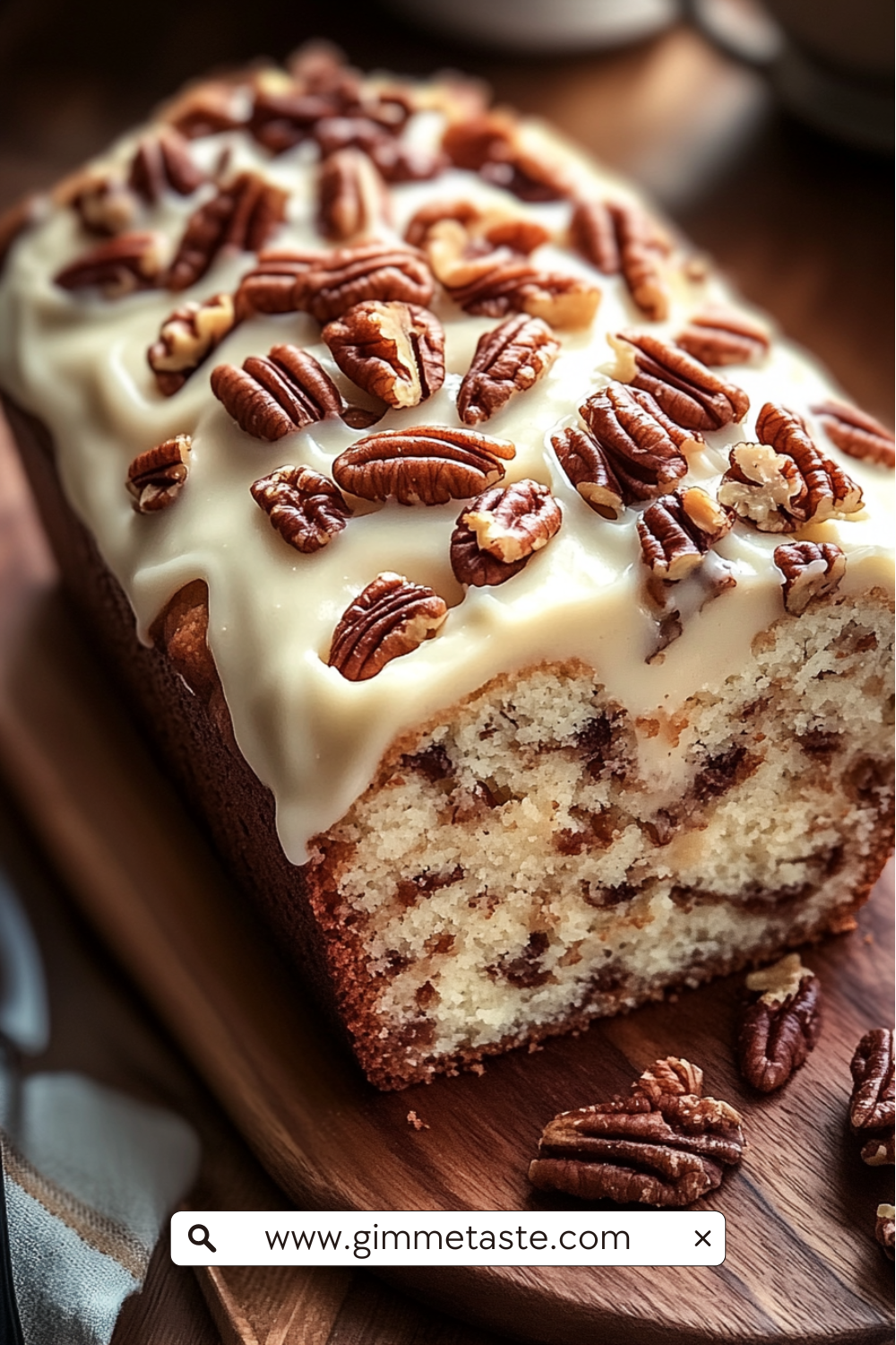 Butter Pecan Cake Loaf with cream cheese icing and toasted pecans on a wooden board, sliced to show its moist, nutty interior.