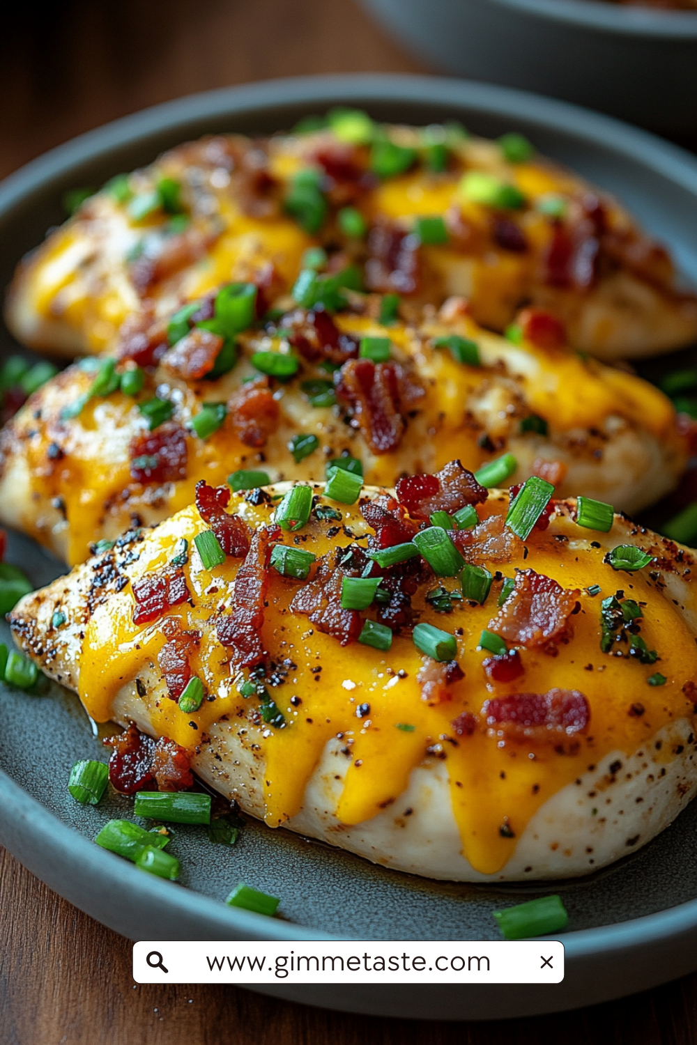 Keto Crack Chicken on a plate, featuring juicy chicken breasts topped with melted cheddar cheese, crispy bacon bits, and chopped green onions, served on a rustic plate.